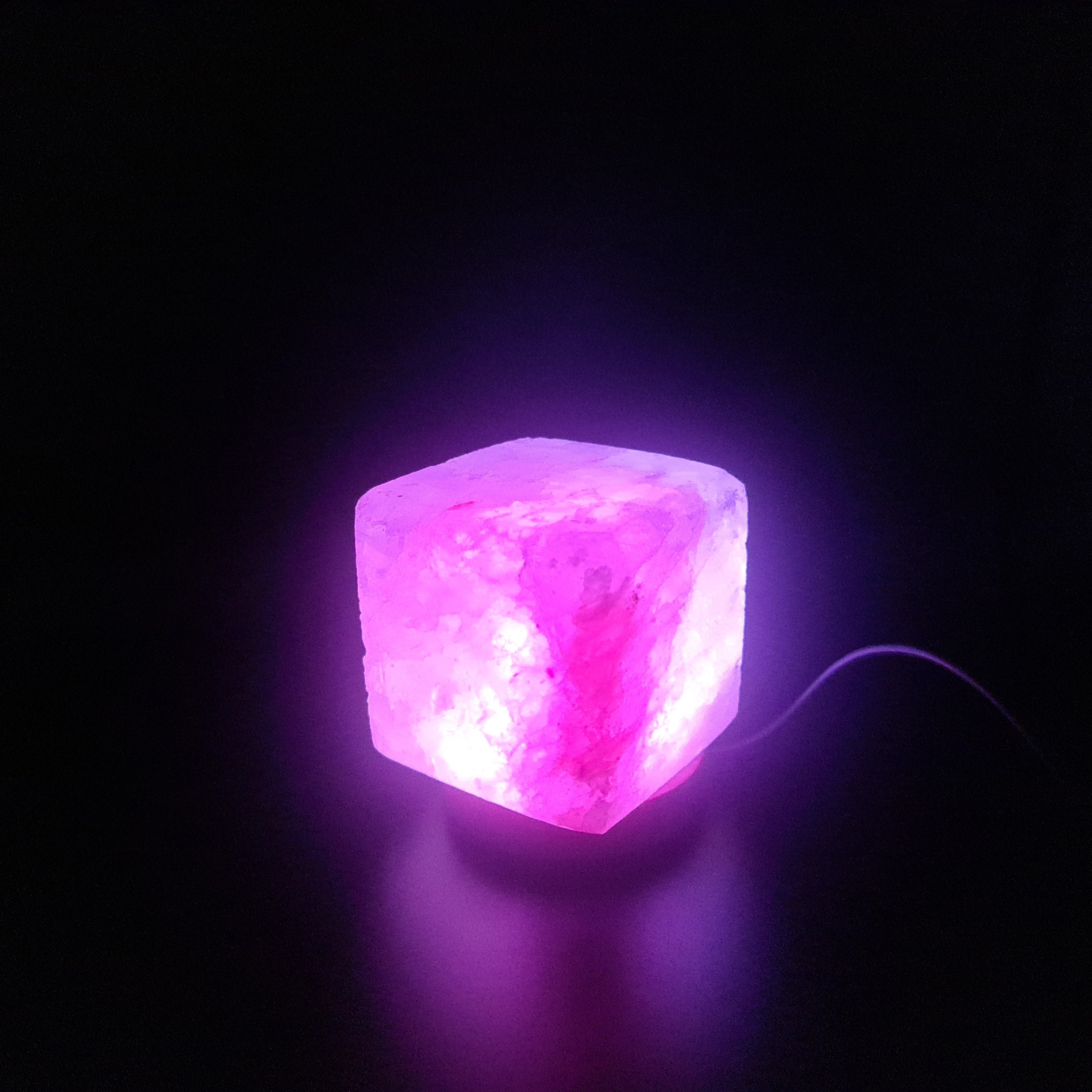 Himalaya USB Farbwechsellampe aus rosa Himalaya-Salz auf Holzsockel, strahlt warmes, beruhigendes Licht aus.