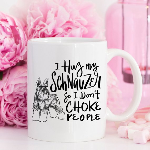 A humorous 11oz coffee mug featuring the phrase 'I Hug My Schnauzer So I Don't Choke People', designed for dog lovers.