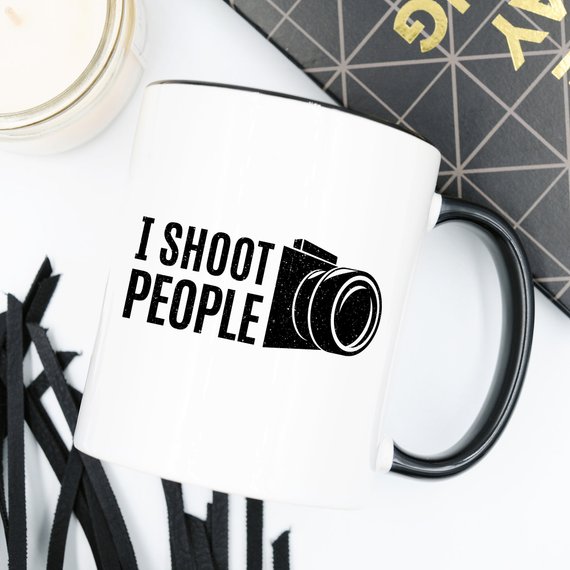 A humorous 11oz ceramic coffee mug with the phrase 'I Shoot People' printed on it, showcasing its glossy finish and sturdy handle.