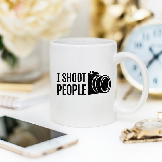 A humorous 11oz ceramic coffee mug with the phrase 'I Shoot People' printed on it, showcasing its glossy finish and sturdy handle.