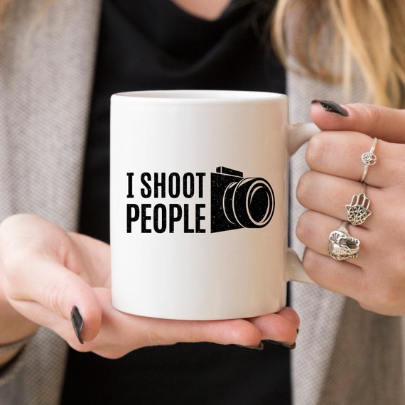 A humorous 11oz ceramic coffee mug with the phrase 'I Shoot People' printed on it, showcasing its glossy finish and sturdy handle.
