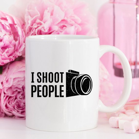 A humorous 11oz ceramic coffee mug with the phrase 'I Shoot People' printed on it, showcasing its glossy finish and sturdy handle.