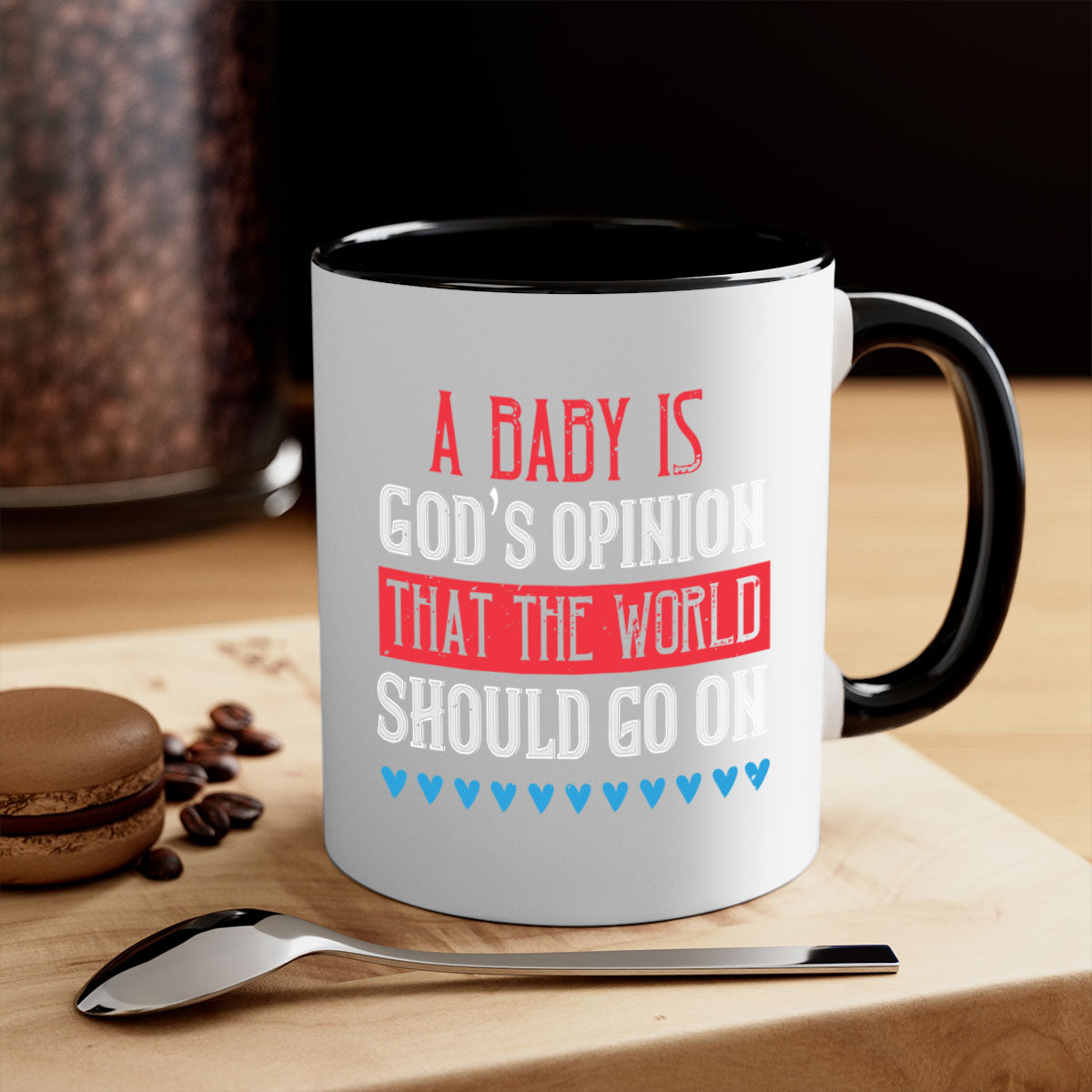 A stylish two-tone ceramic mug with a glossy finish, featuring the phrase 'A baby is God’s opinion that the world should go on' and a comfortable C-shaped handle.