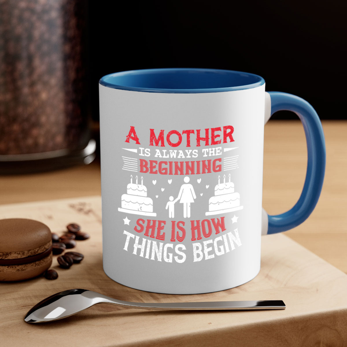 A two-tone ceramic coffee mug with a colored handle and glossy finish, featuring the text 'A Mother is Always the Beginning' for Mother's Day.