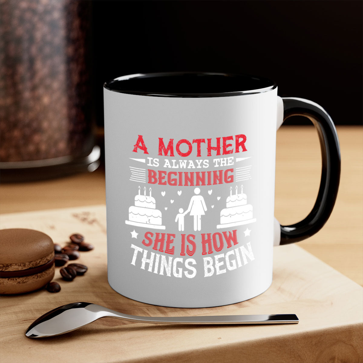 A two-tone ceramic coffee mug with a colored handle and glossy finish, featuring the text 'A Mother is Always the Beginning' for Mother's Day.