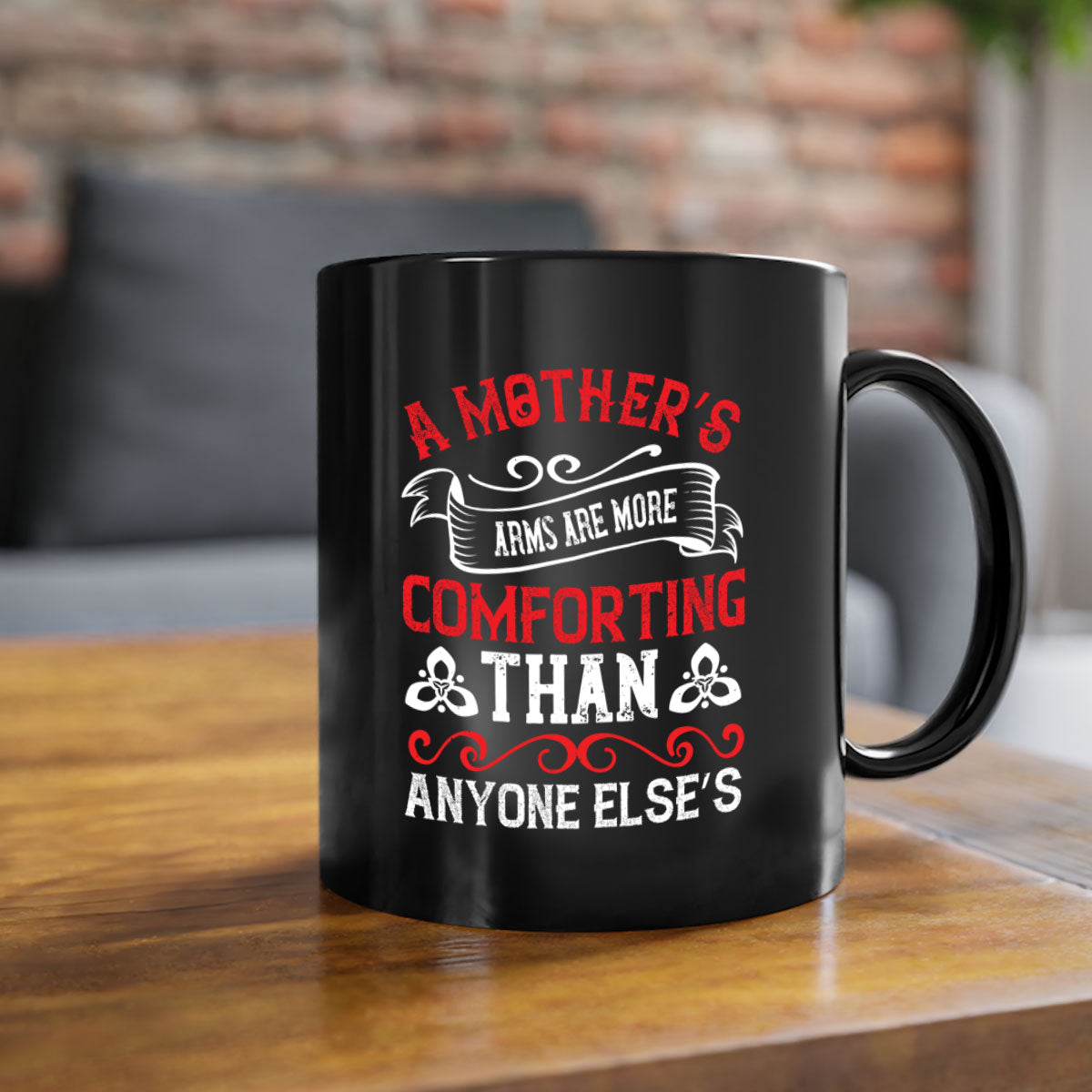 A two-tone ceramic mug with a colored handle and interior, featuring the phrase 'A Mother’s Arms Are More Comforting Than Anyone Else’s'.