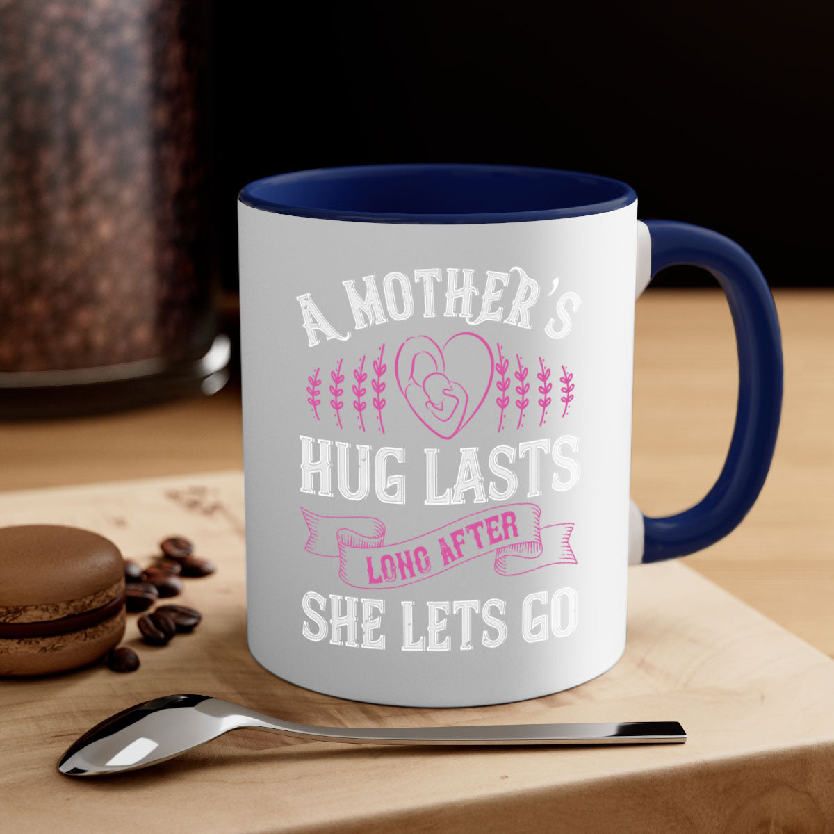 Ceramic coffee mug with a two-tone design featuring a colored handle and interior, showcasing the phrase 'A Mother’s Hug Lasts Long After She Lets Go'.