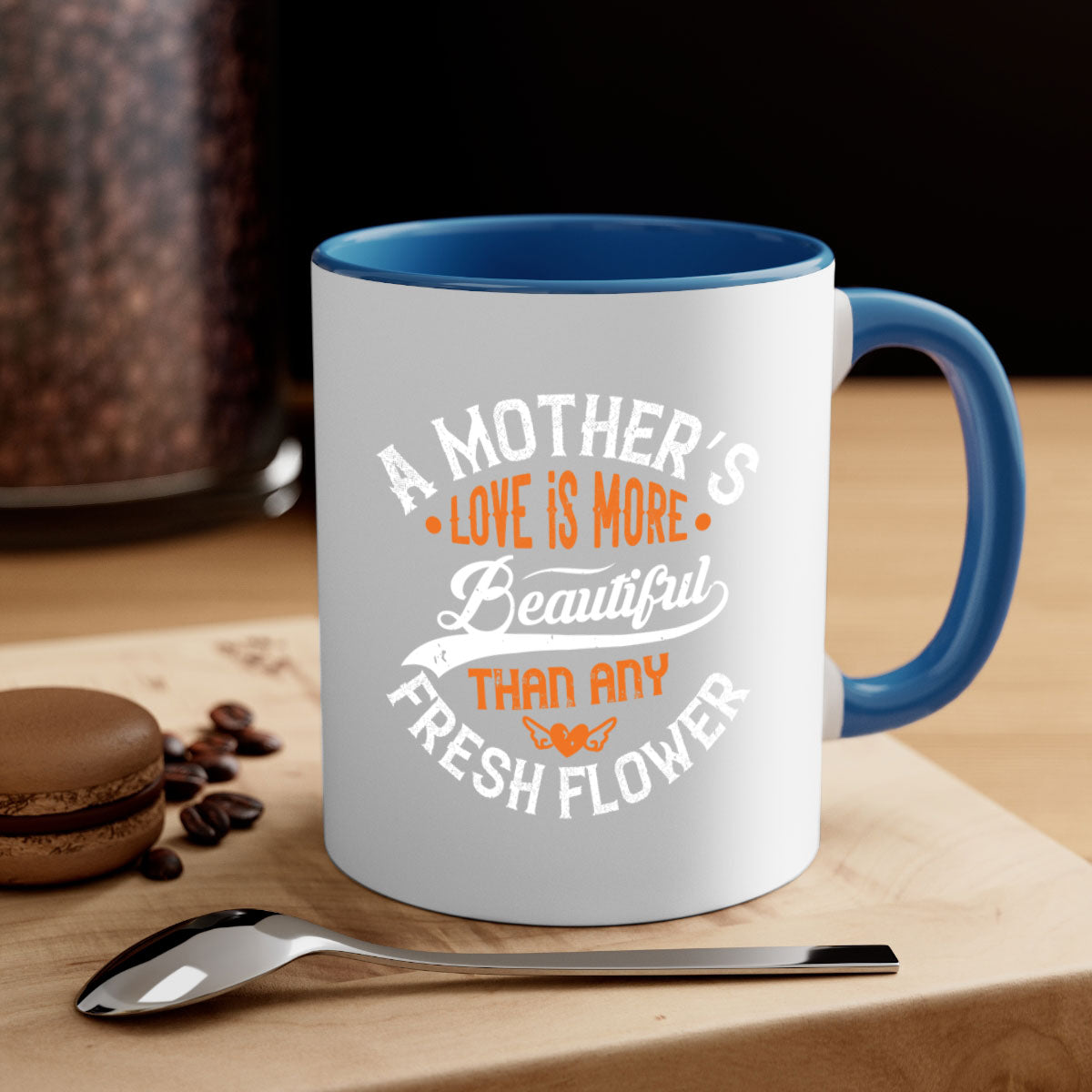 A two-tone ceramic coffee mug with a colored handle and interior, featuring the phrase 'A Mother's Love is More' in an elegant font.
