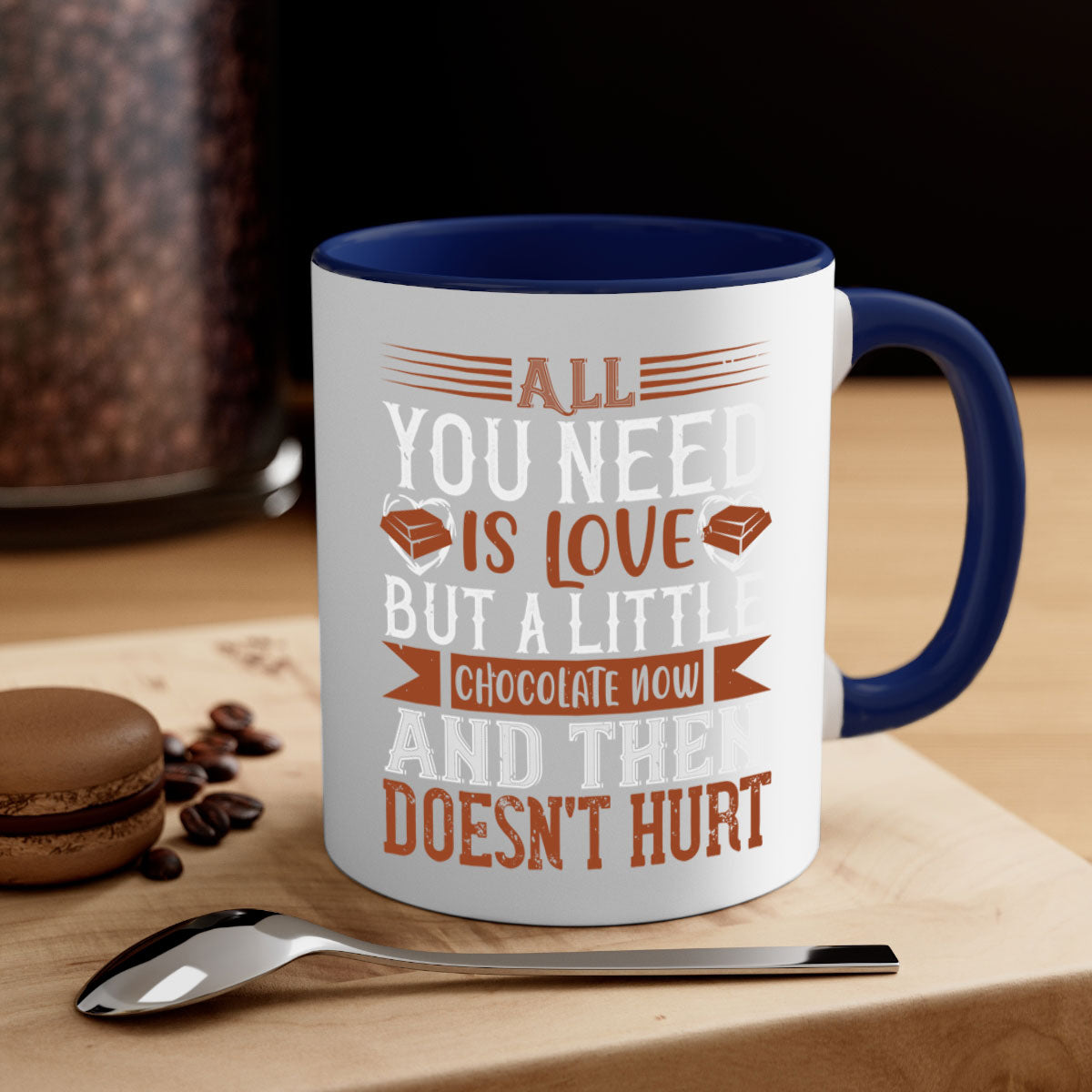 A two-tone ceramic mug with a colored handle and interior, featuring the phrase 'All You Need is Love but a Little Chocolate Now and Then Doesn't Hurt' in a stylish font.