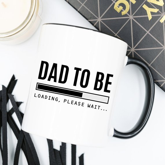 A humorous Baby Announcement Mug featuring 'Dad To Be. Loading, Please W' design, perfect for future dads.