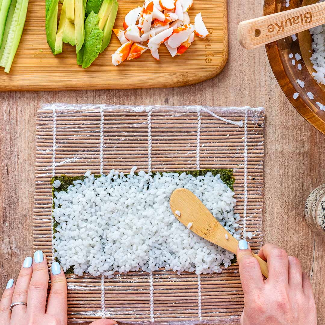 Bamboo Sushi Making Kit featuring two rolling mats, a rice paddle, a rice spreader, and five pairs of reusable chopsticks, all made from sustainable bamboo.