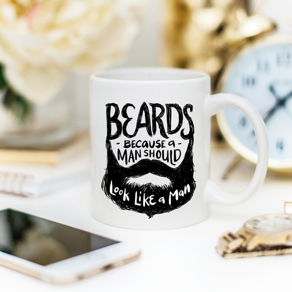 Funny coffee mug with the phrase 'Beards Because A Man Should Look Like A Man' printed on it, showcasing a humorous design.