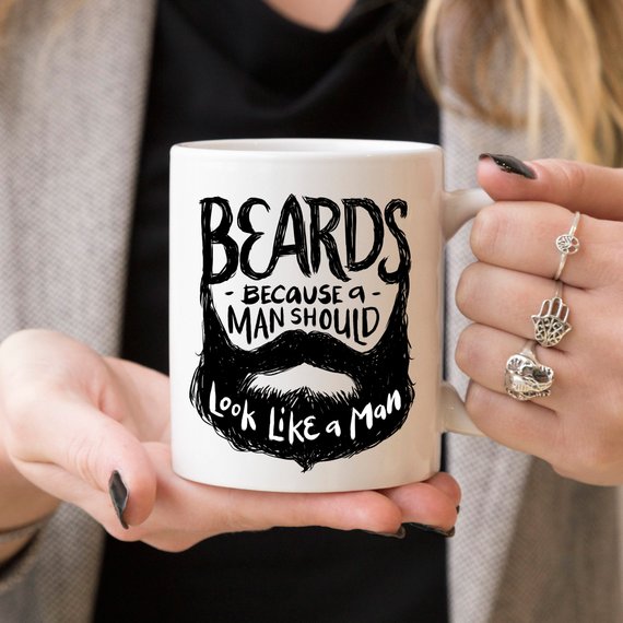 Funny coffee mug with the phrase 'Beards Because A Man Should Look Like A Man' printed on it, showcasing a humorous design.