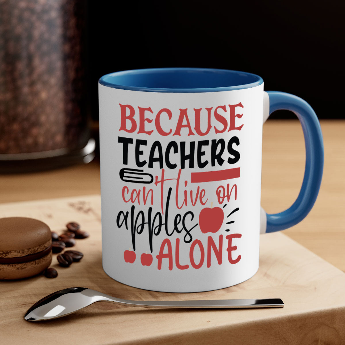 A two-tone ceramic mug with a colored handle and interior, featuring the phrase 'Because Teachers Can't Live on Apples Alone' in a stylish font.