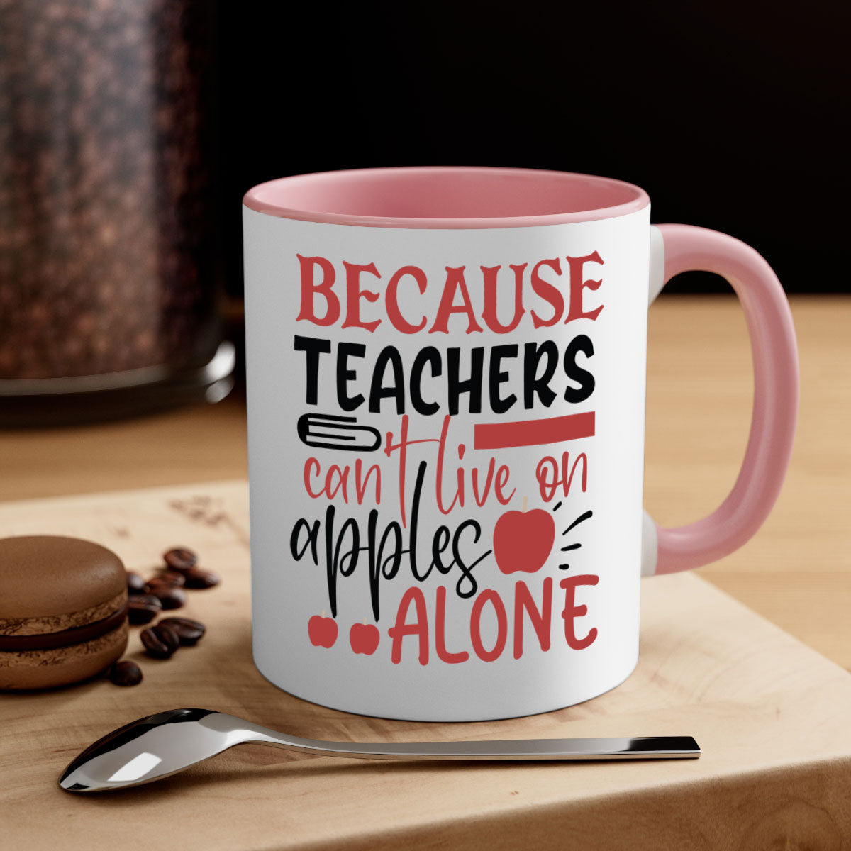 A two-tone ceramic mug with a colored handle and interior, featuring the phrase 'Because Teachers Can't Live on Apples Alone' in a stylish font.