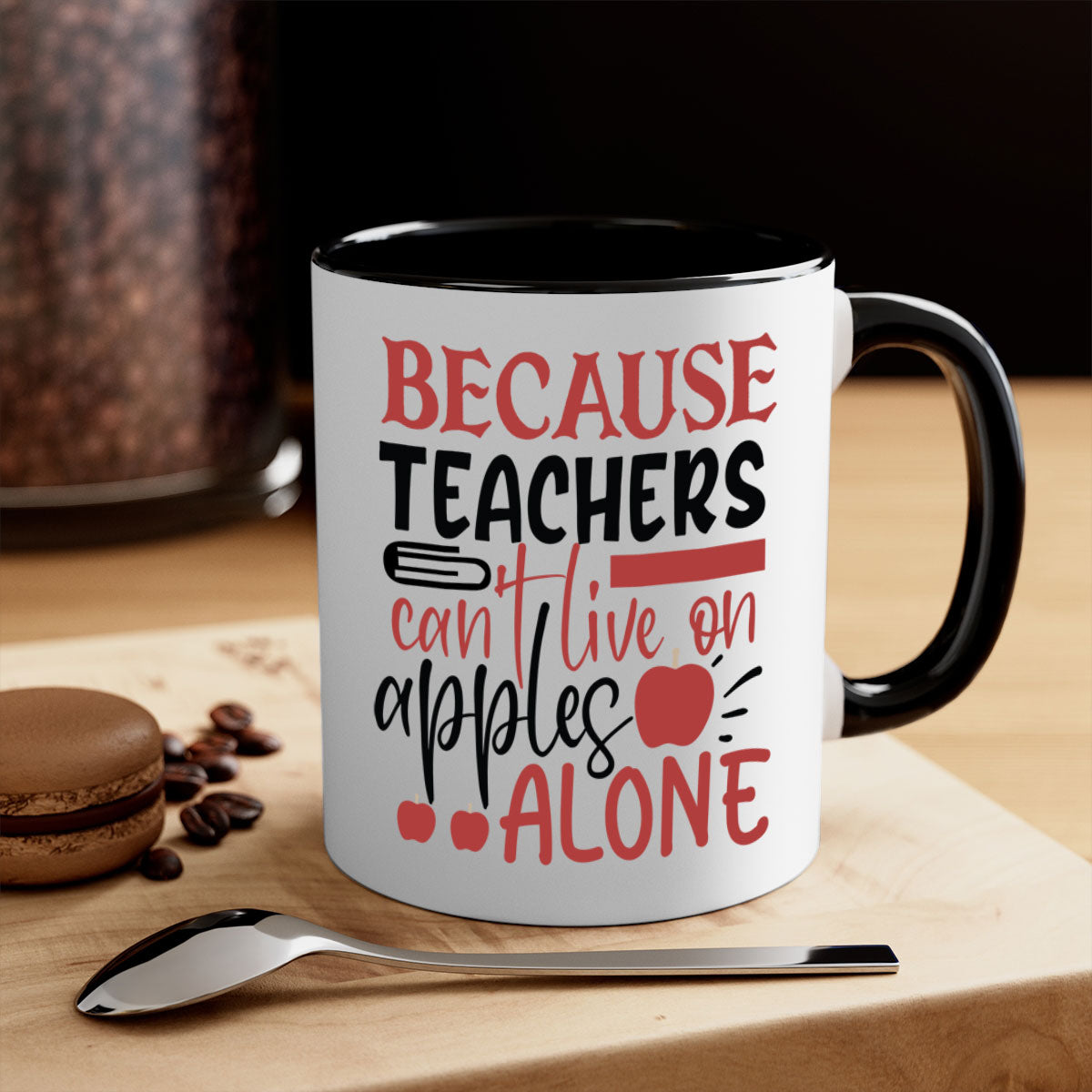 A two-tone ceramic mug with a colored handle and interior, featuring the phrase 'Because Teachers Can't Live on Apples Alone' in a stylish font.