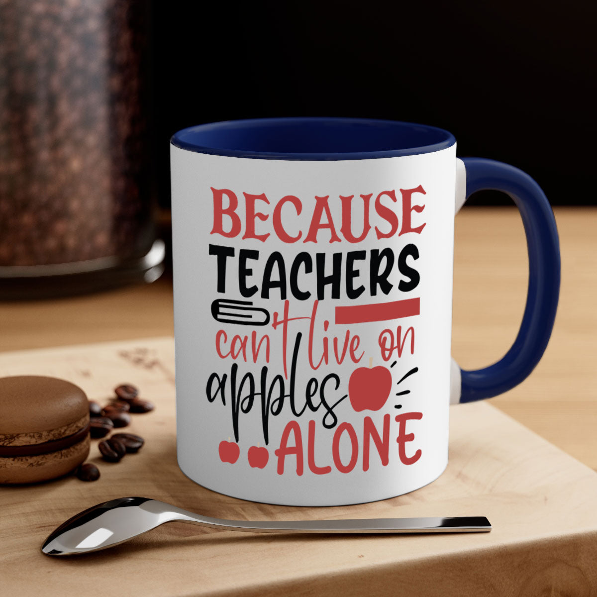 A two-tone ceramic mug with a colored handle and interior, featuring the phrase 'Because Teachers Can't Live on Apples Alone' in a stylish font.