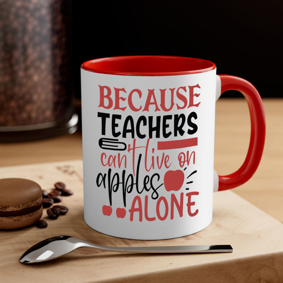 A two-tone ceramic mug with a colored handle and interior, featuring the phrase 'Because Teachers Can't Live on Apples Alone' in a stylish font.