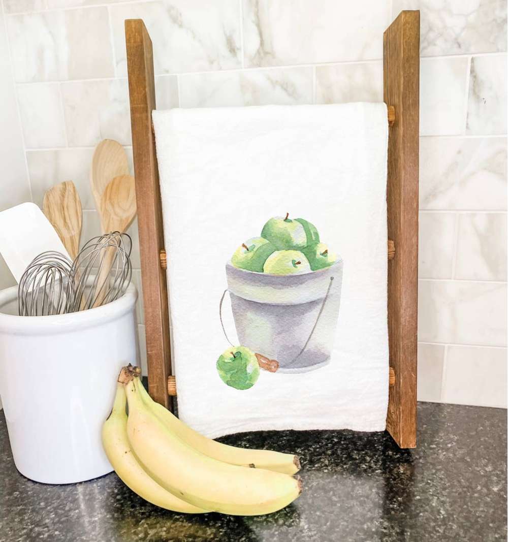 A vibrant cotton tea towel featuring a bucket of green apples design, perfect for kitchen use.