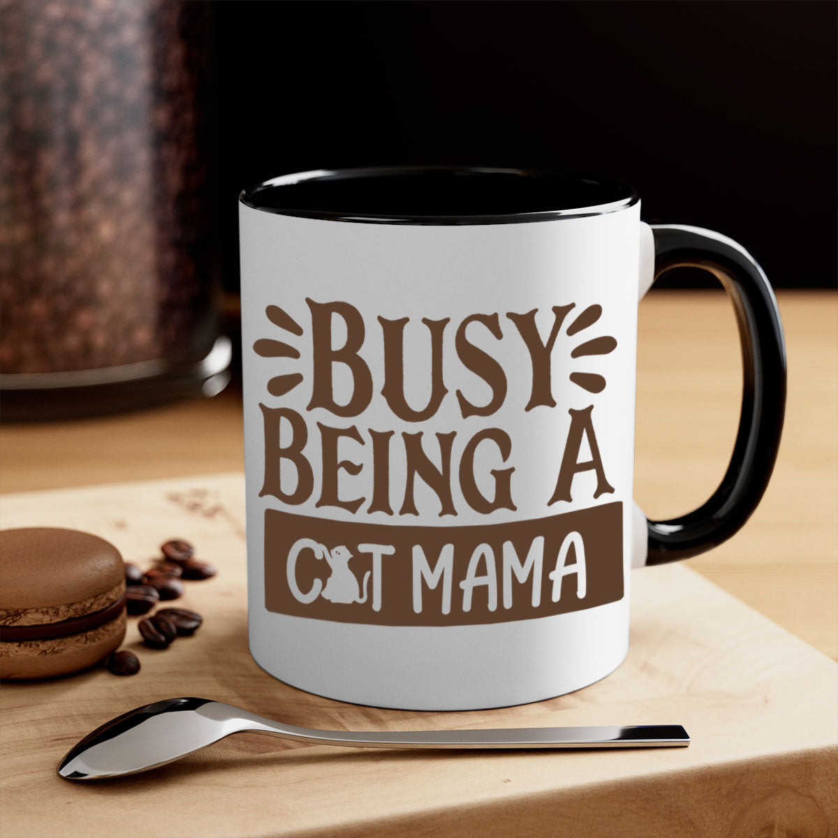 A two-tone ceramic mug with a colored handle and interior, featuring the phrase 'Busy Being A Cat Mama' in a stylish font.