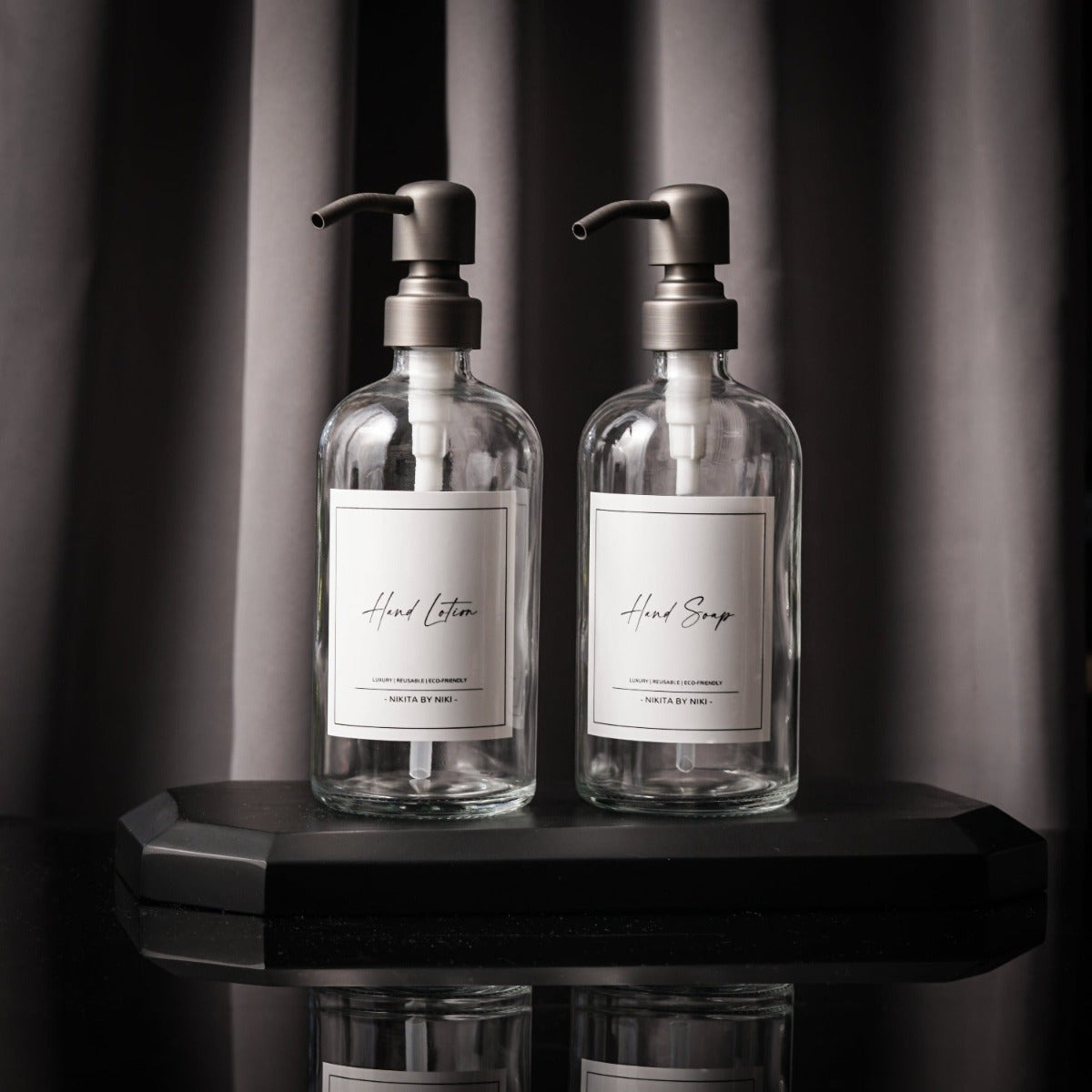 Set of 2 clear glass soap dispensers with matte black stainless steel pumps, ideal for kitchen or bathroom use.