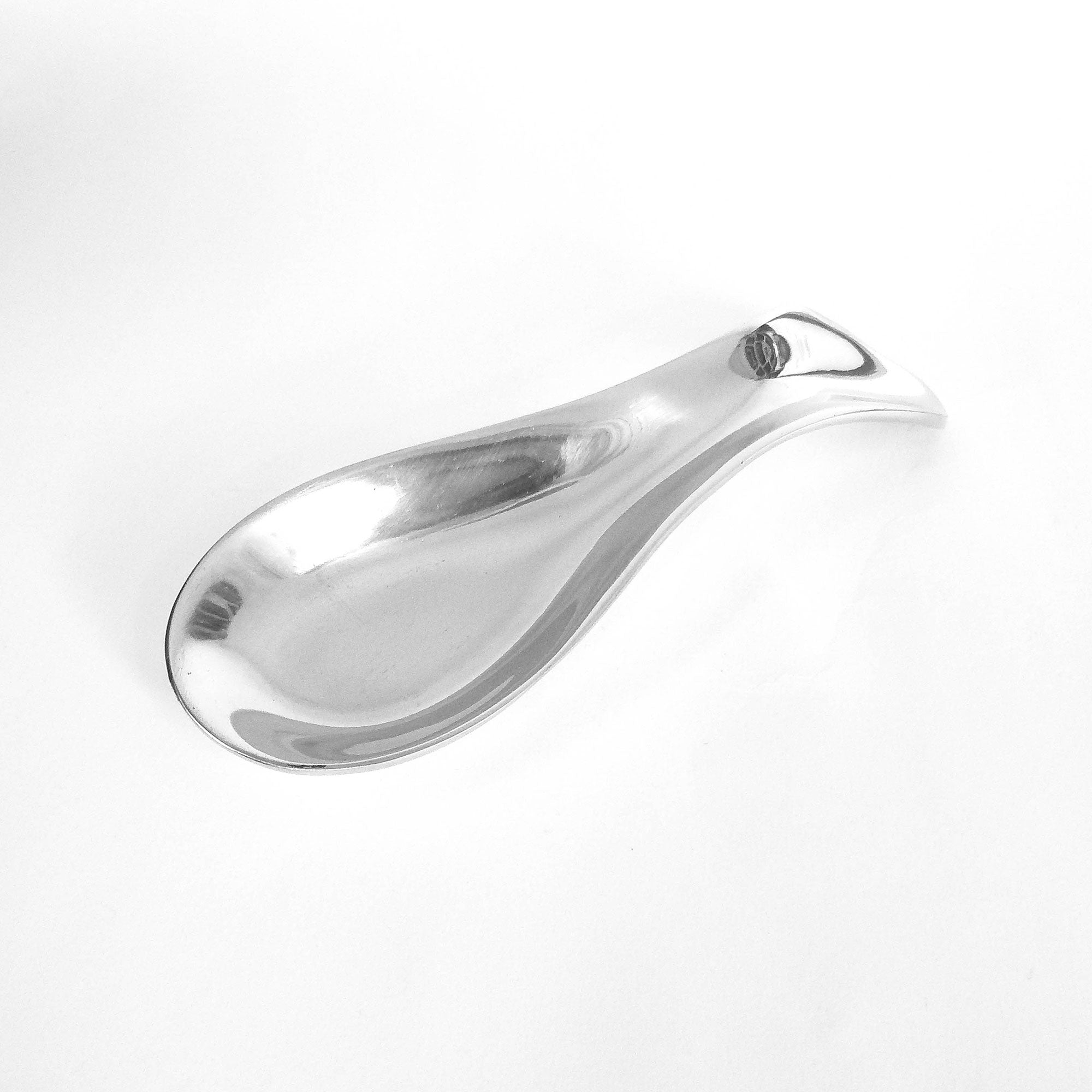Contemporary-designed spoon rest made from recycled aluminum with a chic hand-cast finish, featuring a wavy elongated shape.
