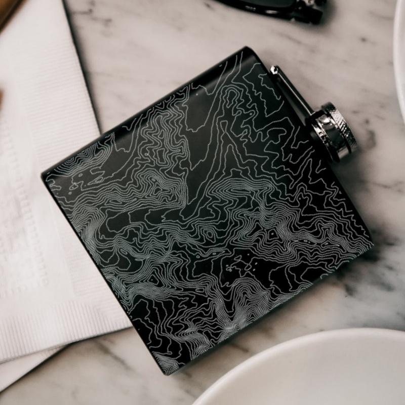 Matte black hip flask featuring a custom engraved map of Denali National Park, Alaska, with coordinates.