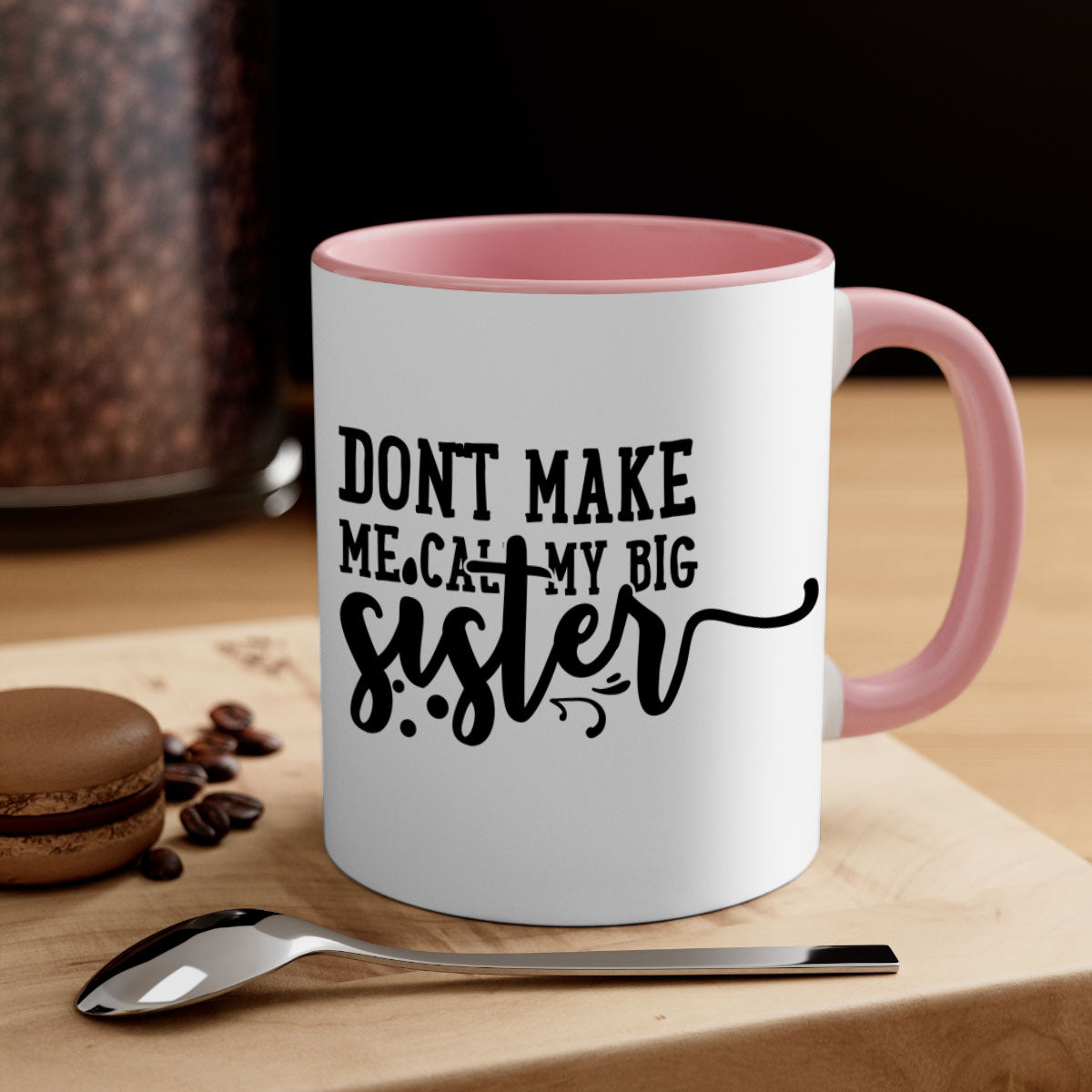 A two-tone ceramic coffee mug with the phrase 'Don't Make Me Call My Big Sister' printed on it, featuring a colored handle and glossy finish.