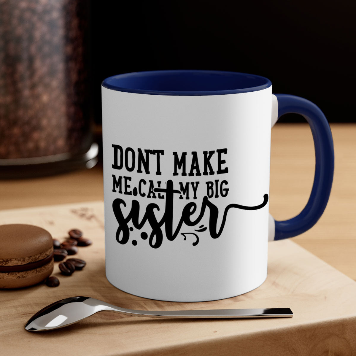 A two-tone ceramic coffee mug with the phrase 'Don't Make Me Call My Big Sister' printed on it, featuring a colored handle and glossy finish.