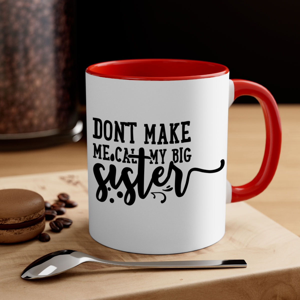 A two-tone ceramic coffee mug with the phrase 'Don't Make Me Call My Big Sister' printed on it, featuring a colored handle and glossy finish.