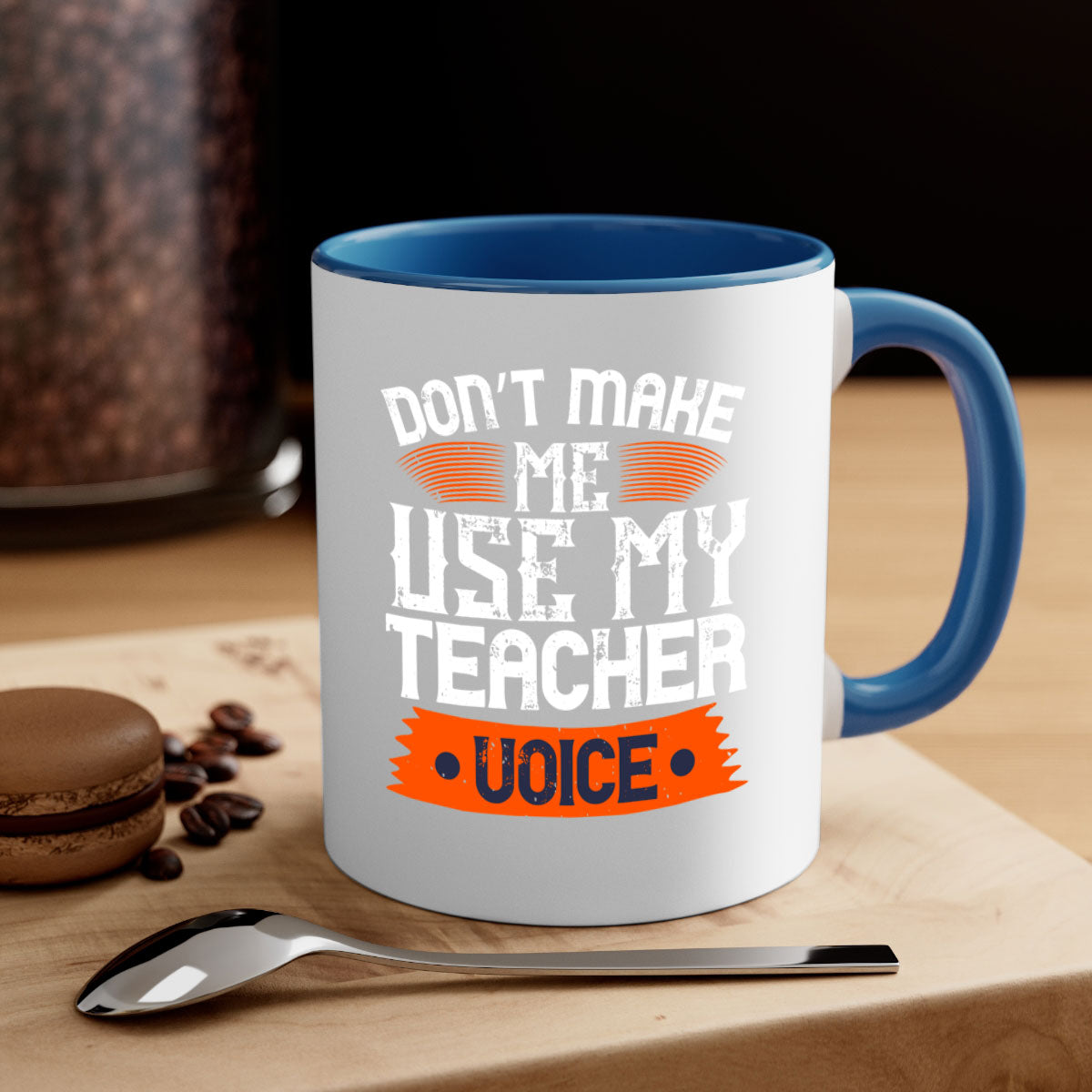 Ceramic coffee mug with a colorful handle and interior, featuring the quote 'Don’t make me use my teacher voice' in a stylish design.