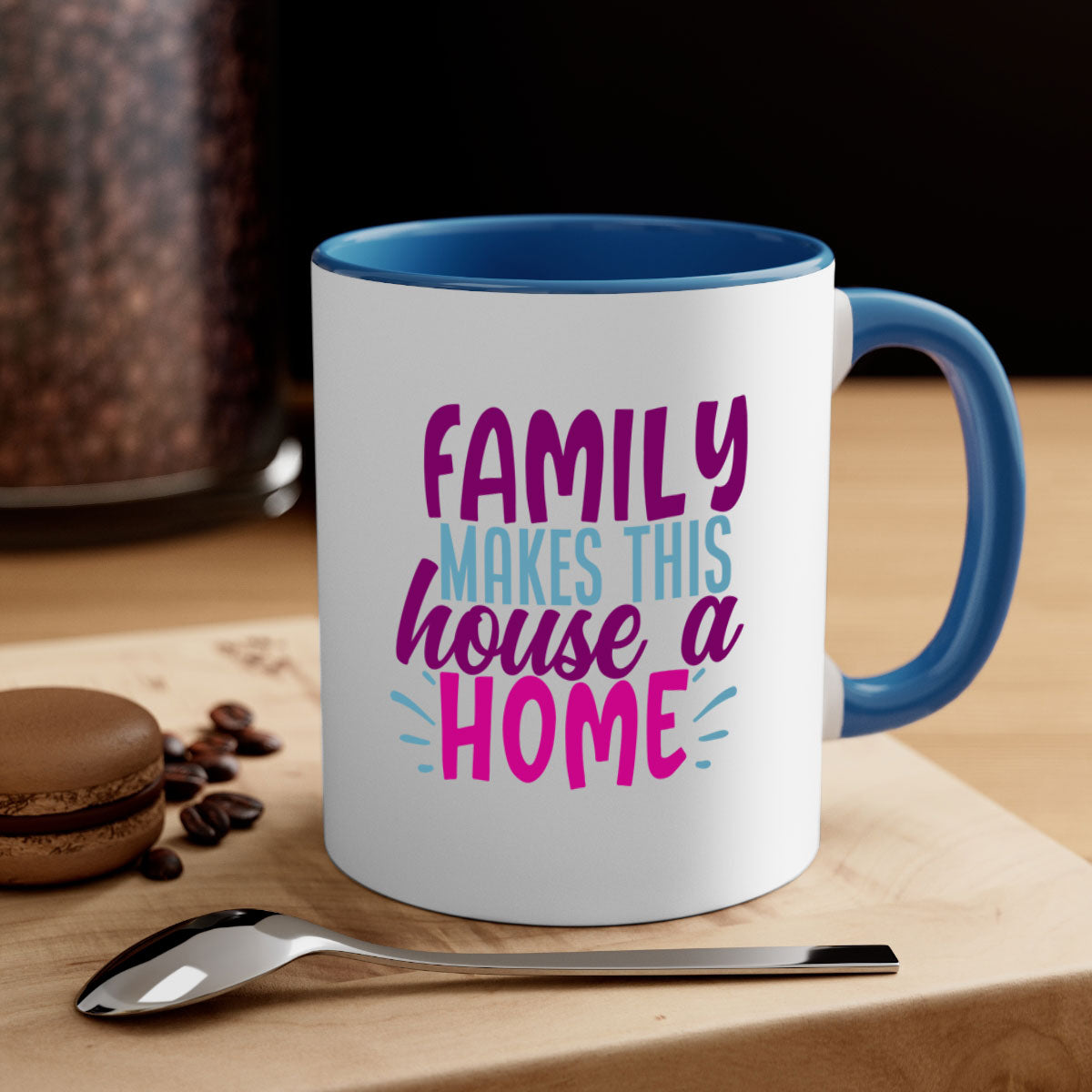 A two-tone ceramic coffee mug with the phrase 'Family Makes This House a Home' printed on it, featuring a colored handle and glossy finish.