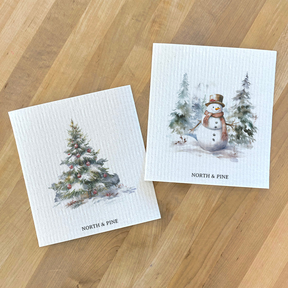 Two Swedish dishcloths featuring a Forest Christmas Tree and a Snowman design, made from eco-friendly materials.
