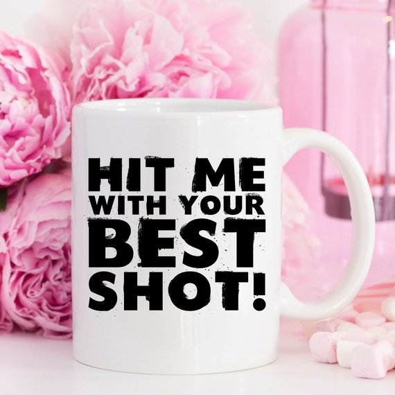 Funny Coffee Mug with 'Hit Me With Your Best Shot' design, crafted from high-grade ceramic, showcasing vibrant print on both sides.