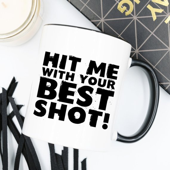 Funny Coffee Mug with 'Hit Me With Your Best Shot' design, crafted from high-grade ceramic, showcasing vibrant print on both sides.