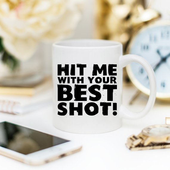 Funny Coffee Mug with 'Hit Me With Your Best Shot' design, crafted from high-grade ceramic, showcasing vibrant print on both sides.