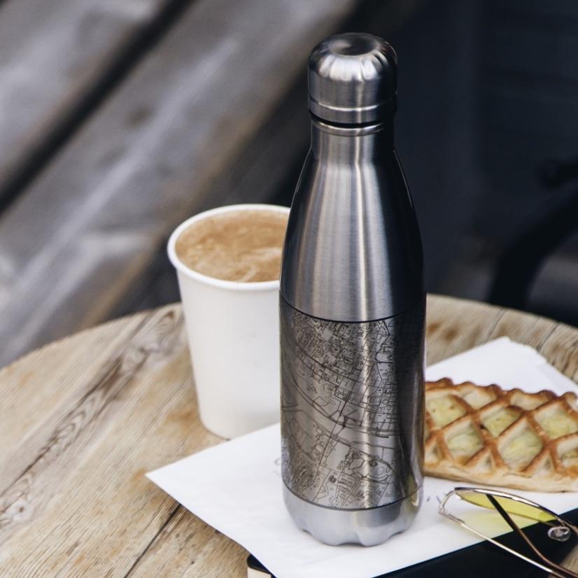 A 17oz insulated stainless steel bottle featuring a custom engraved map of Glacier National Park, Alaska, showcasing its stunning topography.