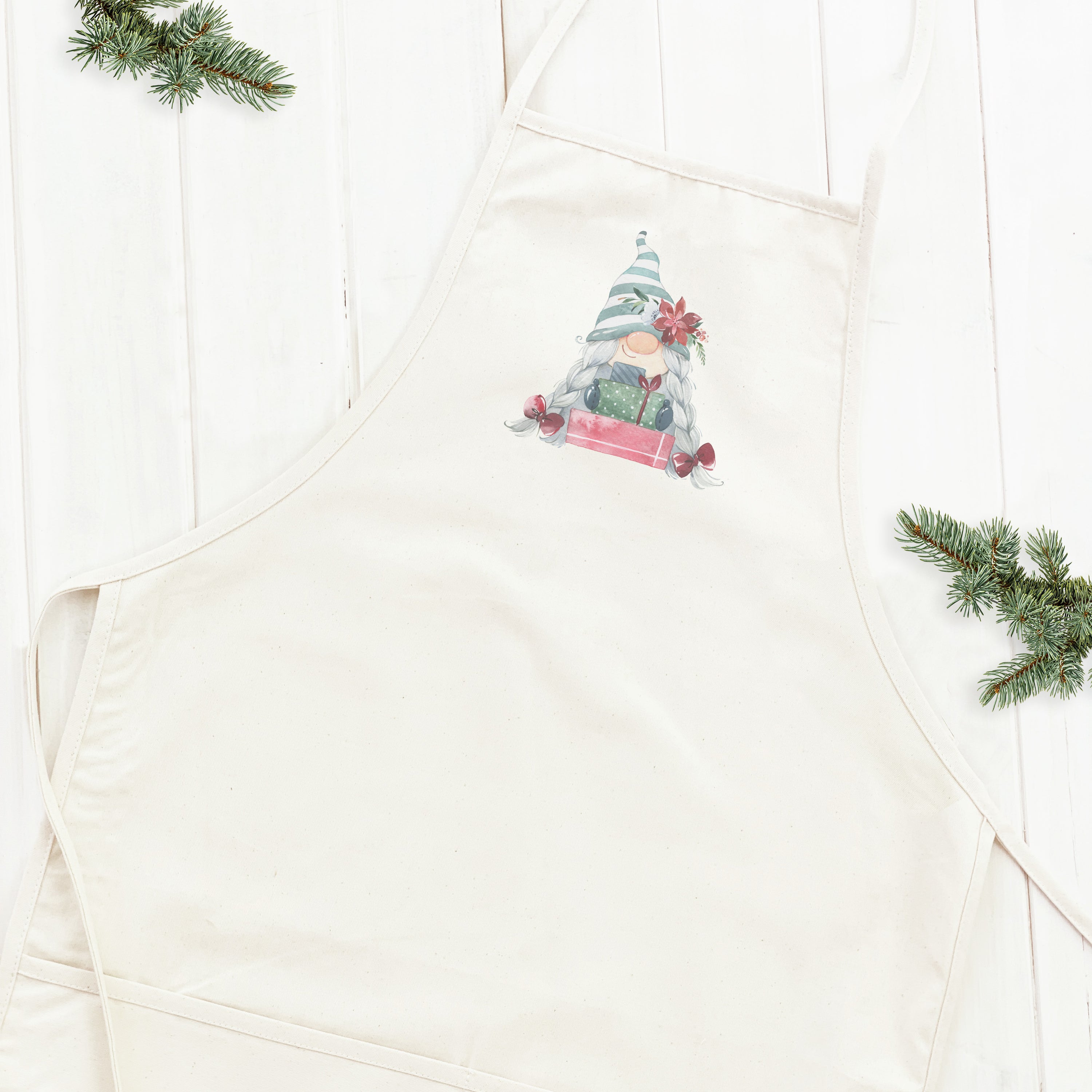 A stylish women's apron featuring a whimsical gnome design with presents, made from durable cotton canvas.