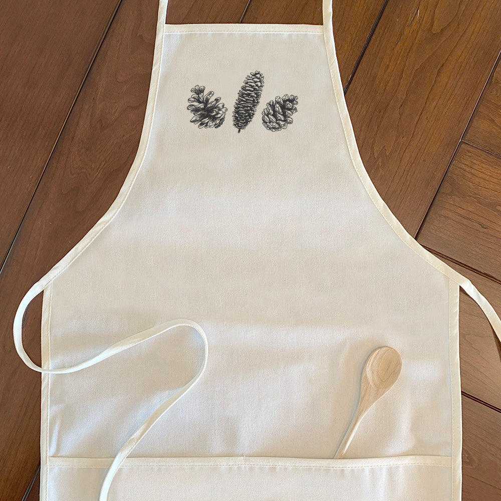 A stylish women's apron featuring a hand-drawn pinecone design, made from durable cotton canvas with natural twill ties.