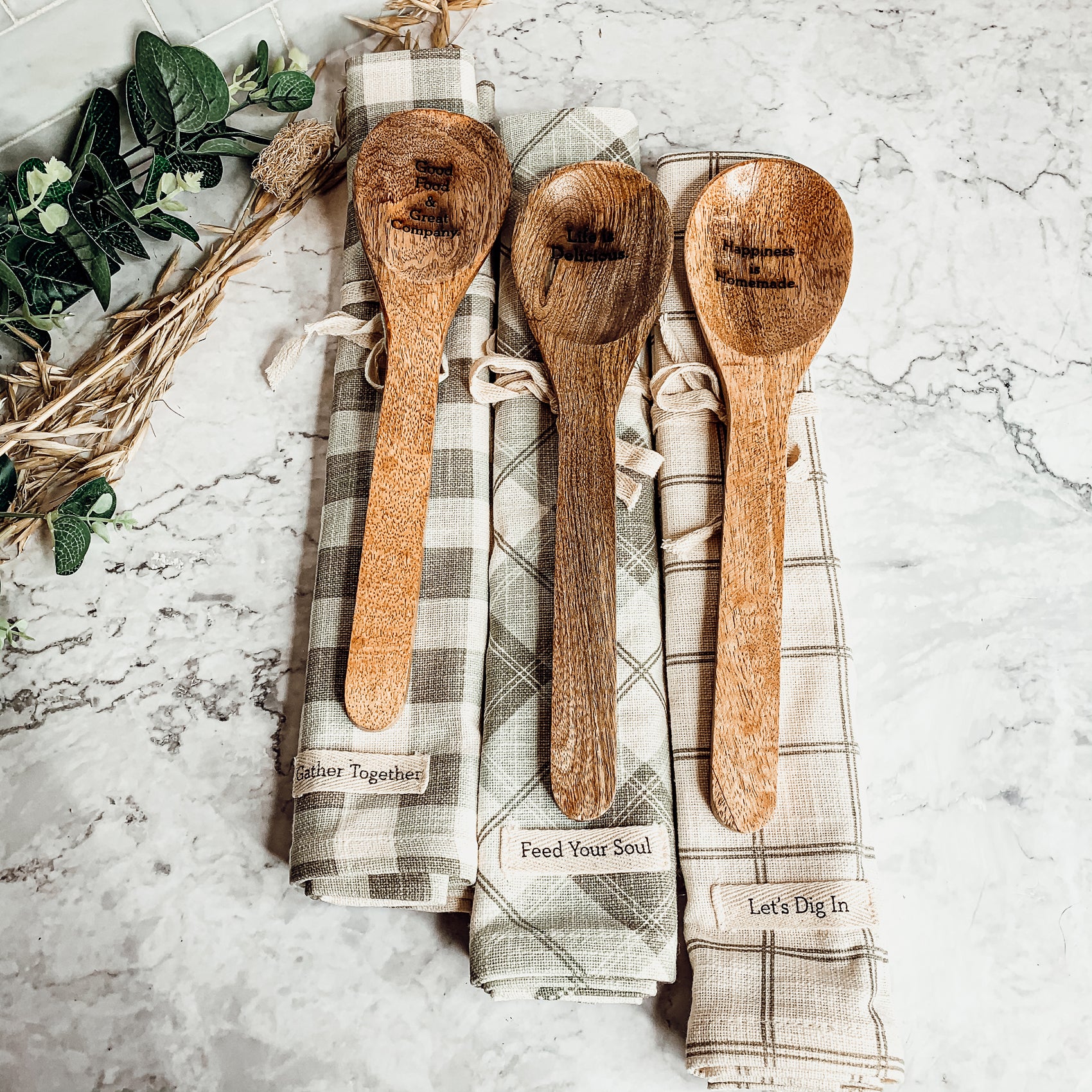 Happiness Is Home Set featuring a decorative dish towel and a wooden spoon with engraved sayings, perfect for gifting.