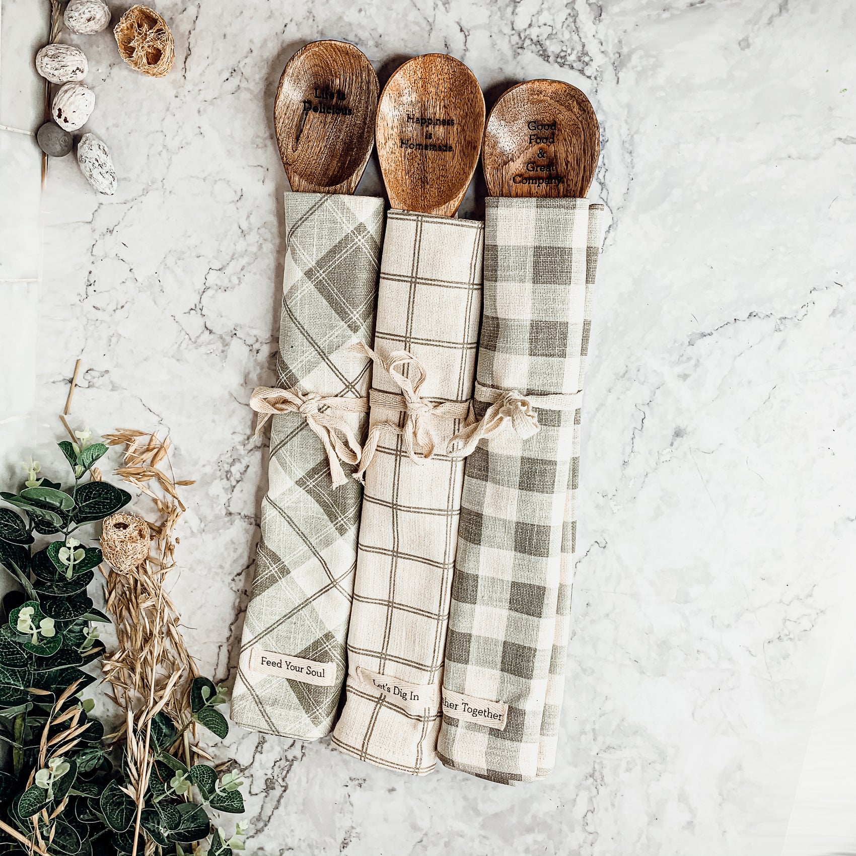 Happiness Is Home Set featuring a decorative dish towel and a wooden spoon with engraved sayings, perfect for gifting.