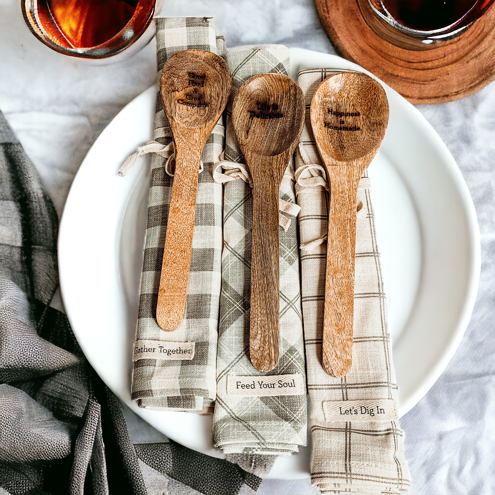 Happiness Is Home Set featuring a decorative dish towel and a wooden spoon with engraved sayings, perfect for gifting.
