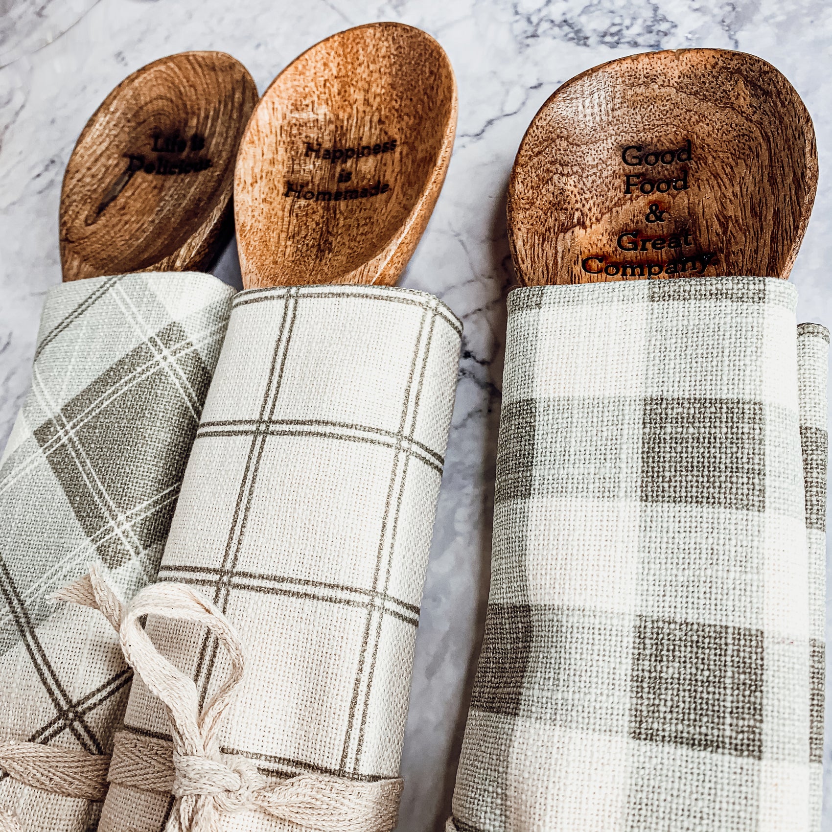 Happiness Is Home Set featuring a decorative dish towel and a wooden spoon with engraved sayings, perfect for gifting.