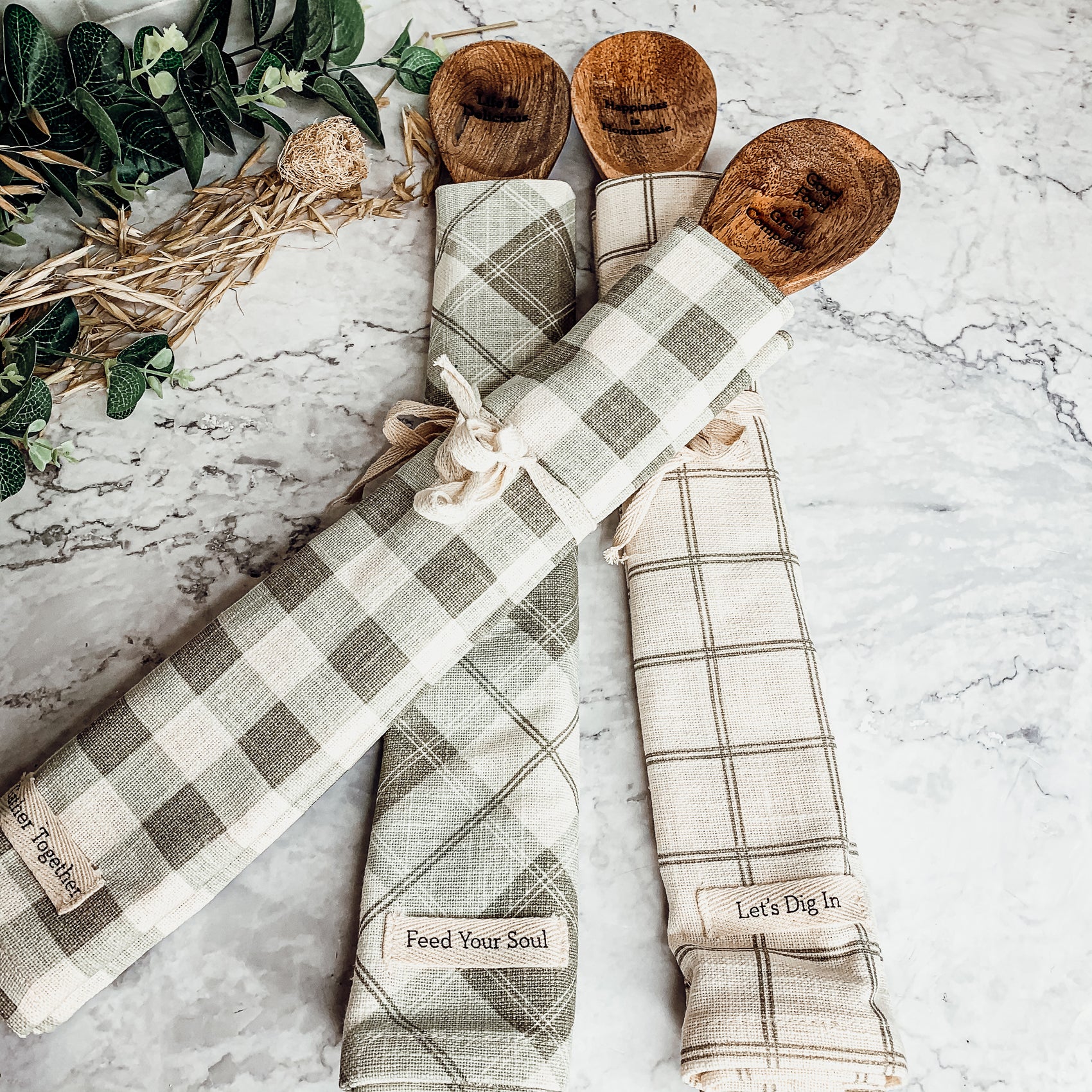 Happiness Is Home Set featuring a decorative dish towel and a wooden spoon with engraved sayings, perfect for gifting.