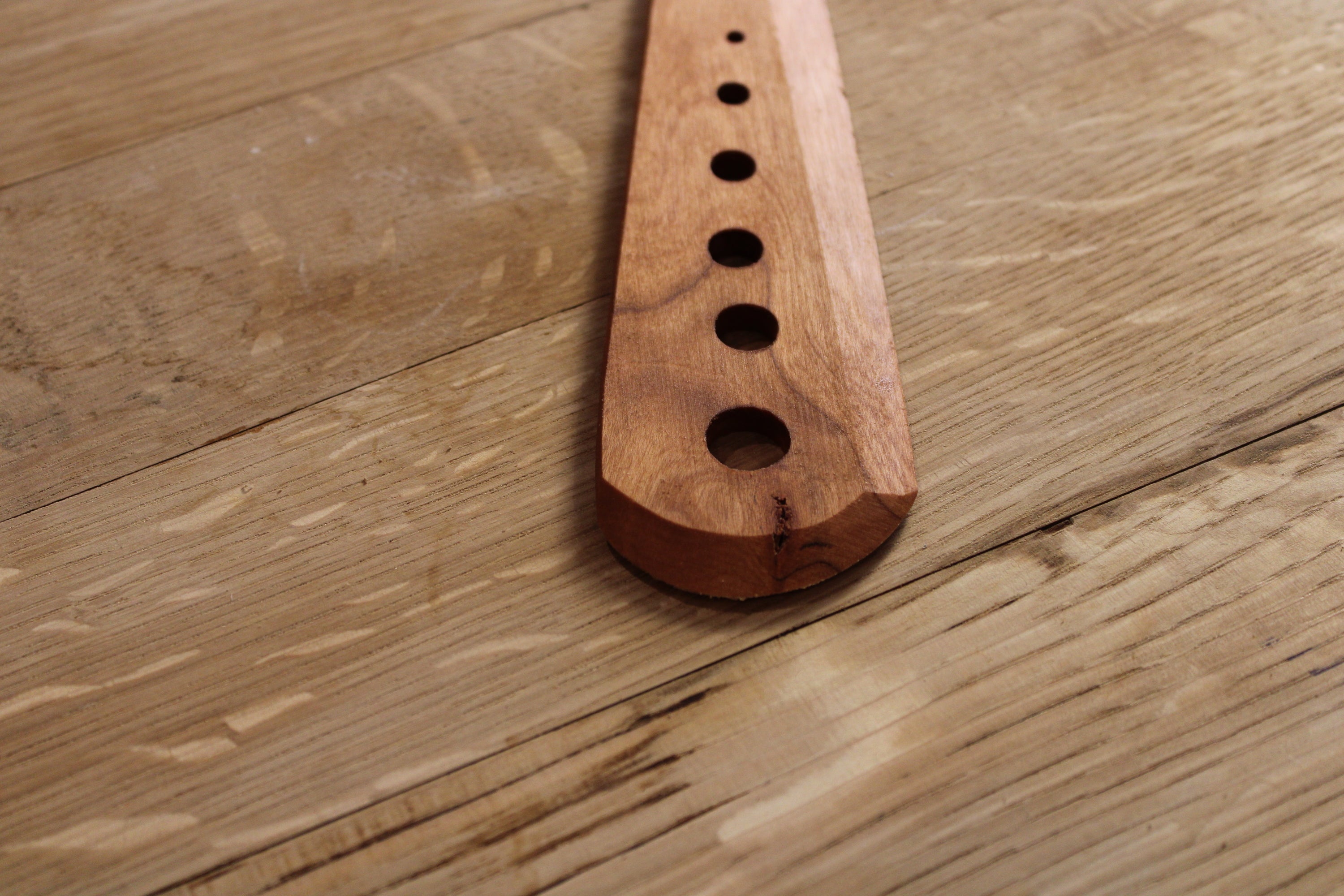 Herb Stripper gardening tool made of wood, featuring multiple sizes for stripping herbs and leaves, with a long scraper side for cutting and bruising.