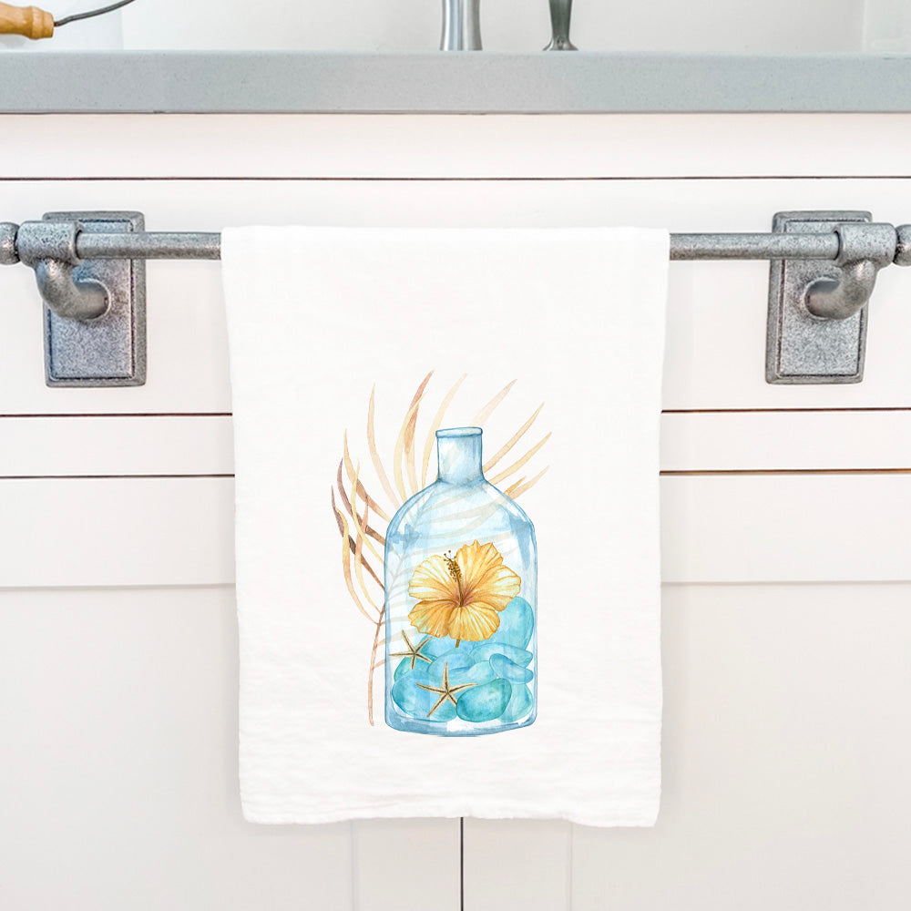 Hibiscus in a Bottle cotton tea towel featuring vibrant floral design, hemmed edges, and 27-inch square size.