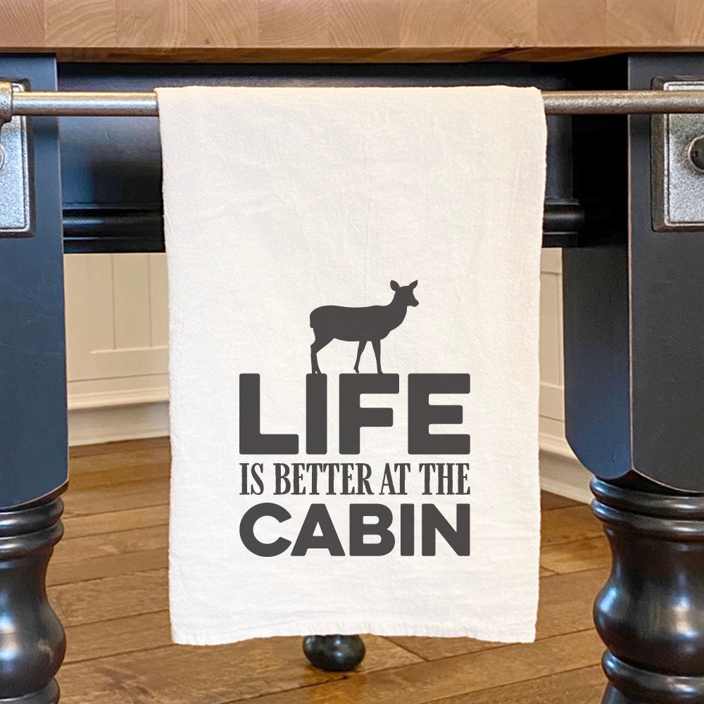 Cotton tea towel featuring a deer design with the phrase 'Life is Better at the Cabin', perfect for kitchen decor.