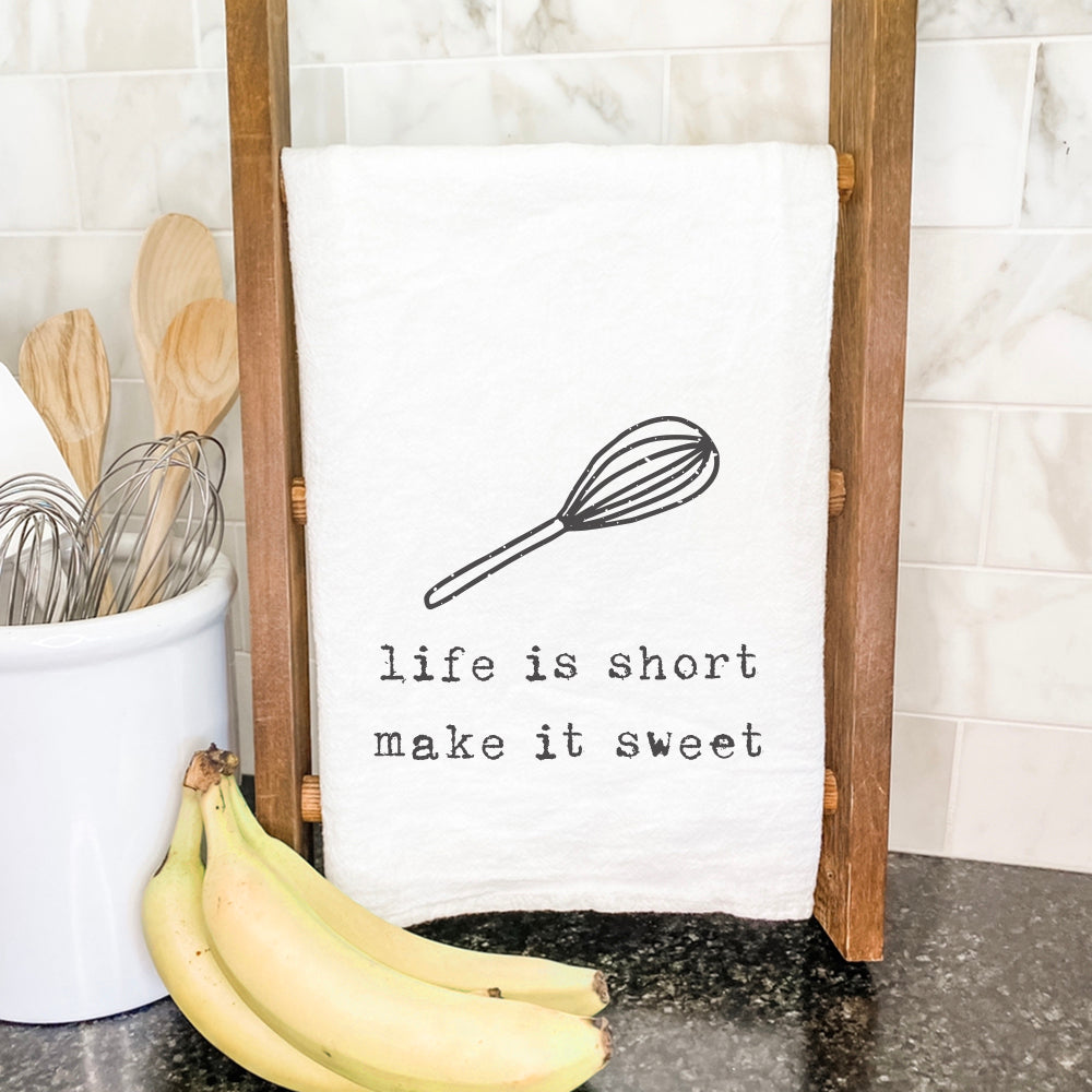 A vibrant cotton tea towel featuring the phrase 'Life is Short' with a whisk design, perfect for kitchen use.