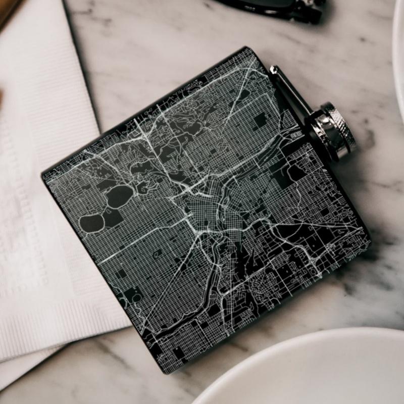 Custom engraved matte black hip flask featuring a Minneapolis map and coordinates, complete with a canvas bag and funnel.