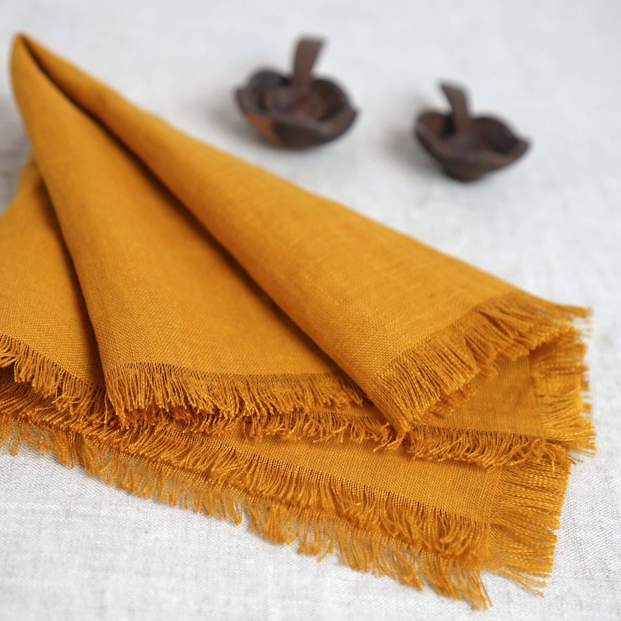 Set of two mustard linen napkins with tassels, showcasing a soft texture and elegant design, perfect for modern dining decor.